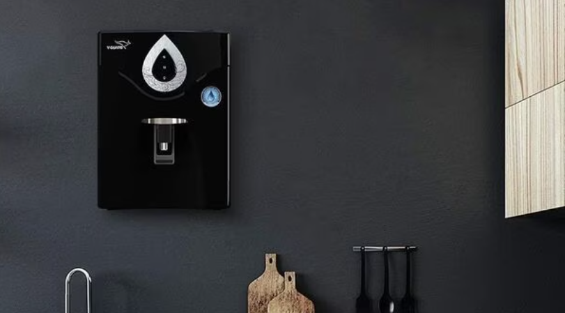 In this blog "Best Water Purifier in Amazon Revealed: What to Buy for Clean Water in 2025" the image have black background wall, and hanging a black colored water purifier